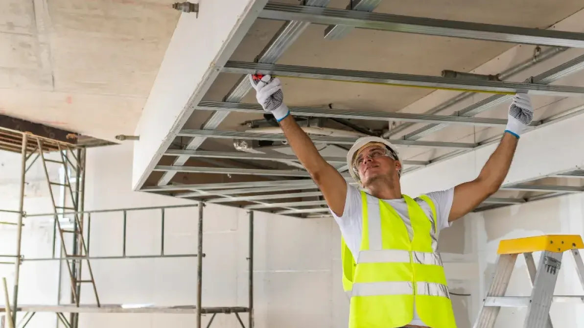 Plaquiste professionnel posant une plaque de plâtre sur un chantier de rénovation