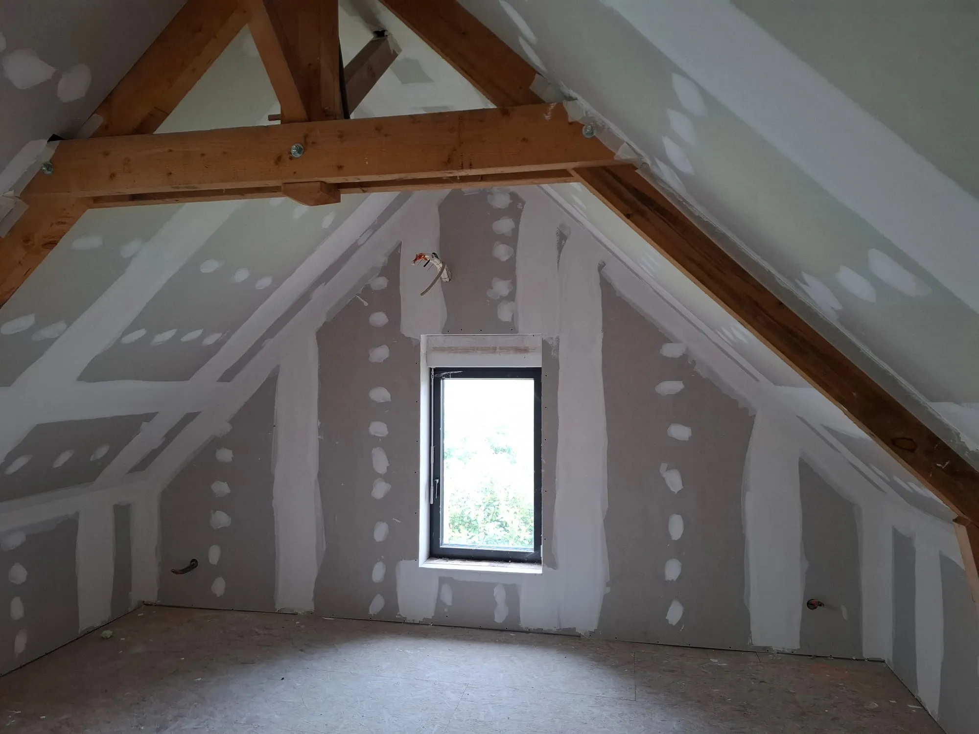 Chambre aménagée dans les combles avec rampants en plaques de plâtre et fenêtre de toit