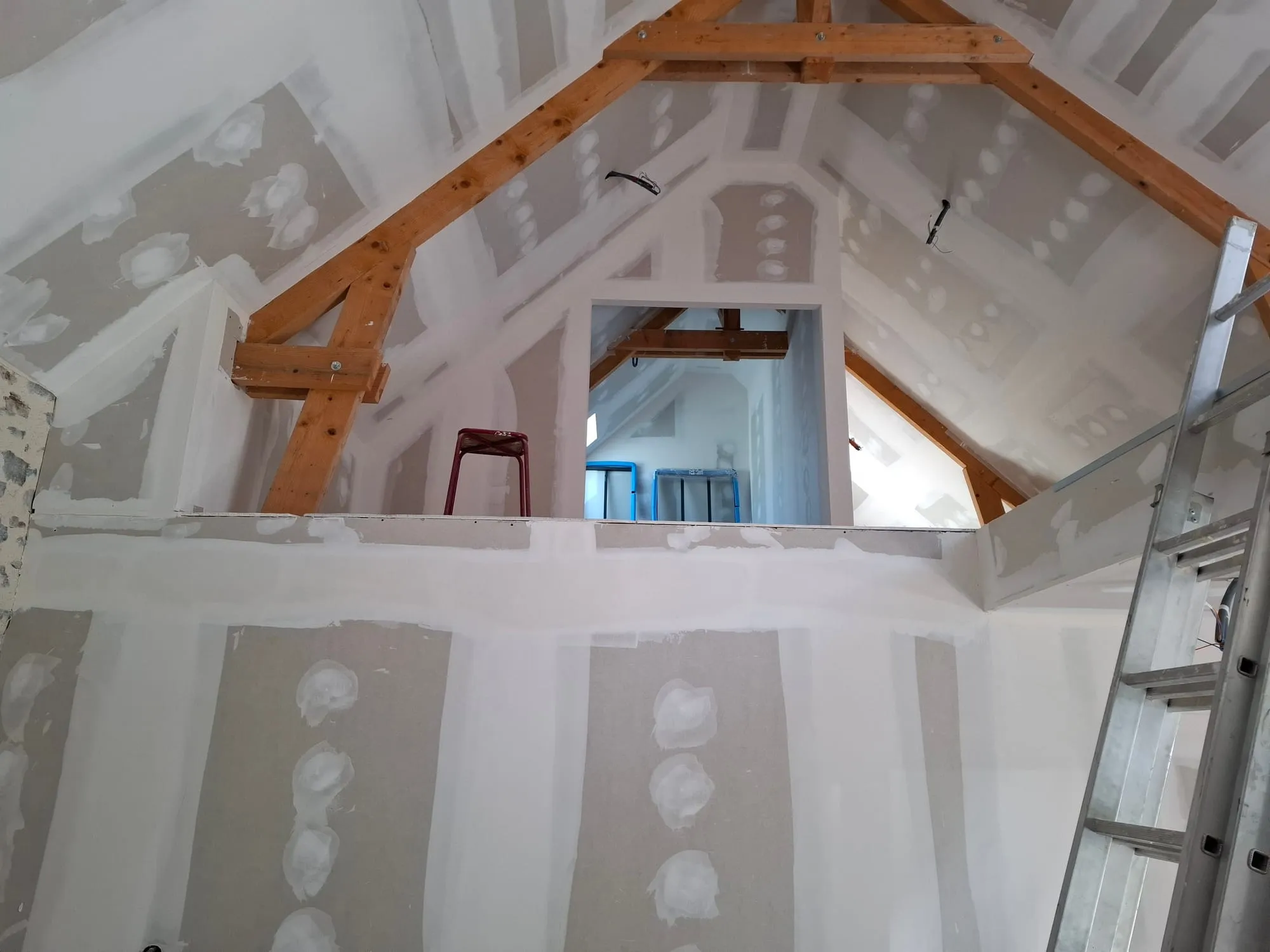 Aménagement des combles en placo avec mezzanine et rampants isolés sous une charpente en bois