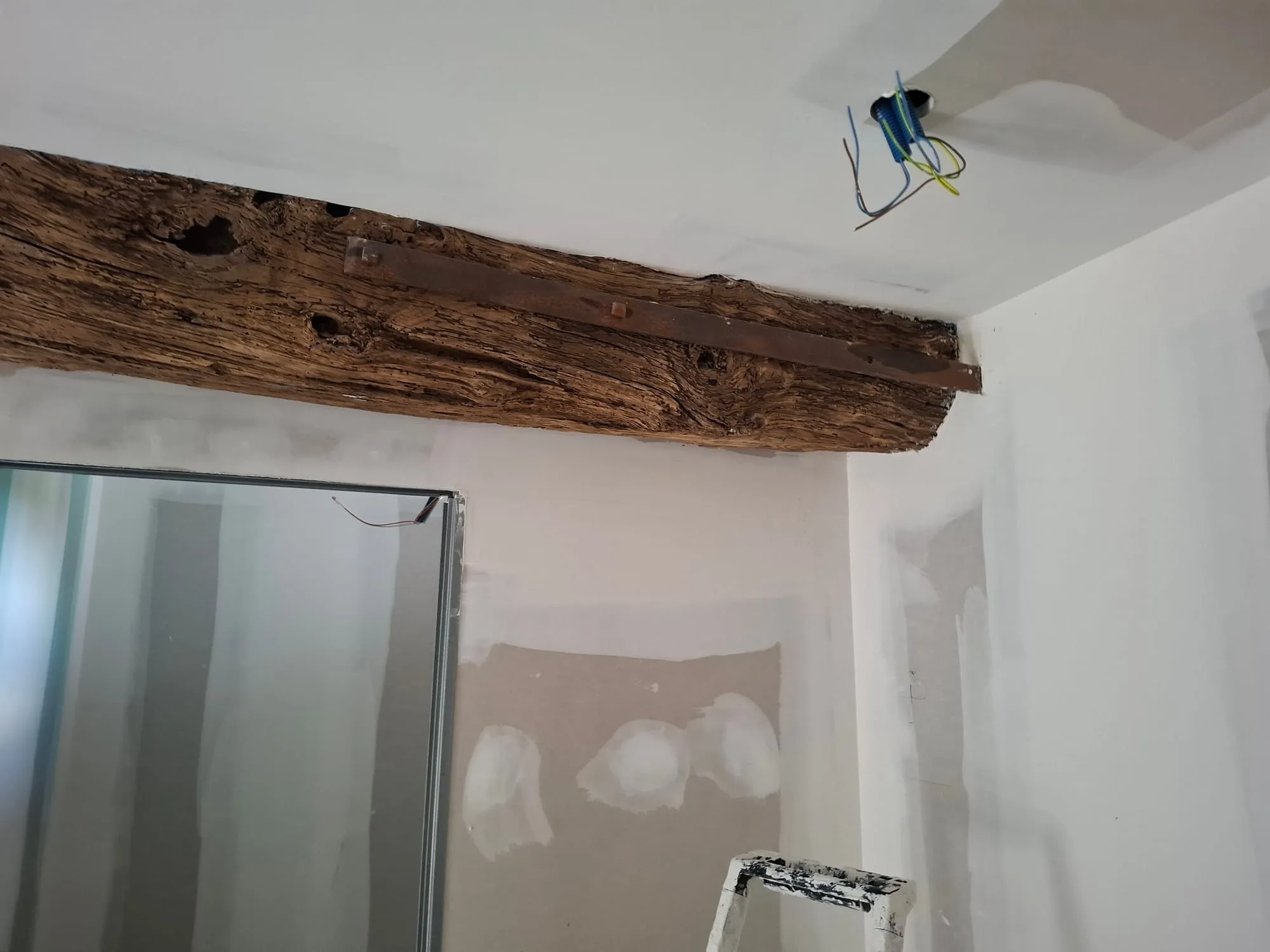 Poutre ancienne conservée au plafond au-dessus d'une cloison de salle d'eau en placo