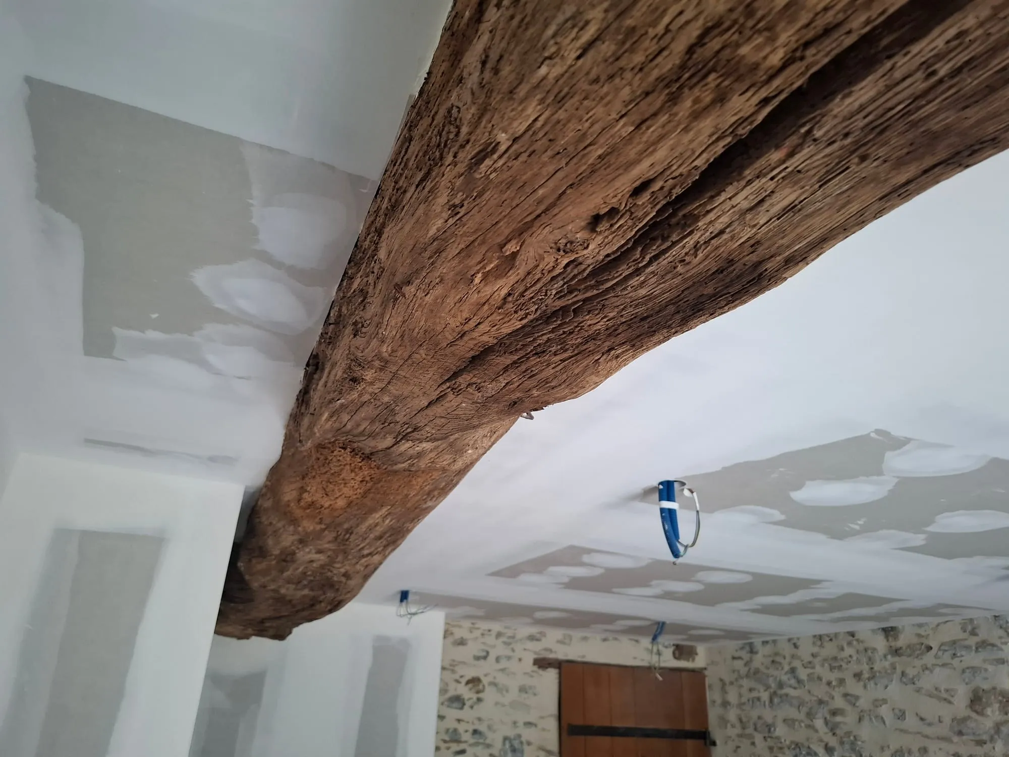 Plafond en placo intégrant une poutre maîtresse en chêne au-dessus d'un mur en pierre
