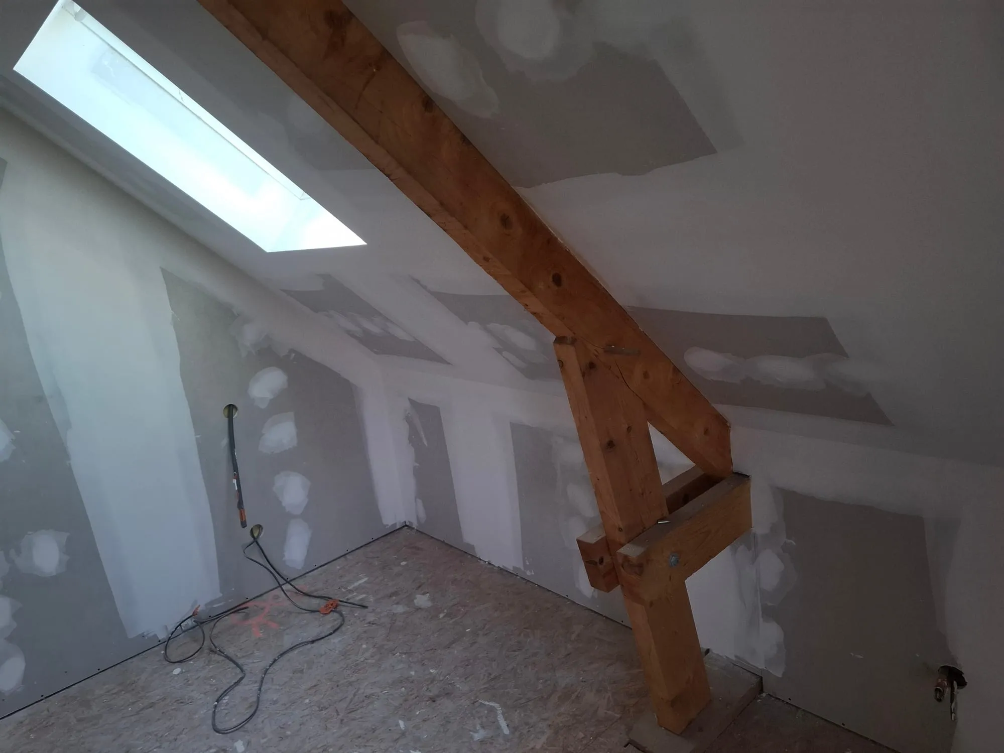 Enfilade de pièces aménagées dans les combles avec plaques de plâtre et poutres